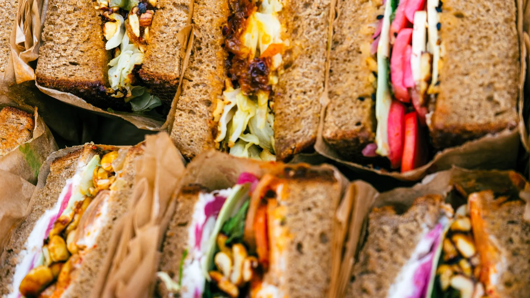 Mehrere angeschnittene Stullen auf Natursauerteigbrot, dicht nebeneinander in Papier gewickelt